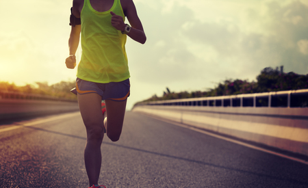 Young fitness woman running on city roadの写真素材