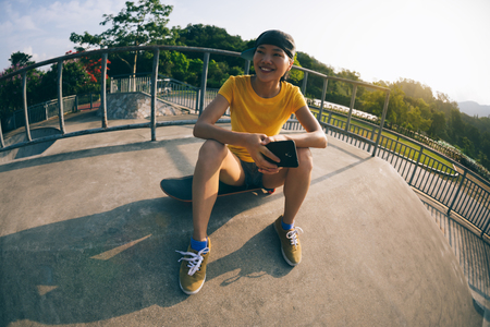 skateboarder sit on skateboard use mobile phone の写真素材