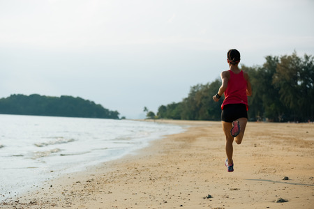 Young woman running on sandy beachの写真素材