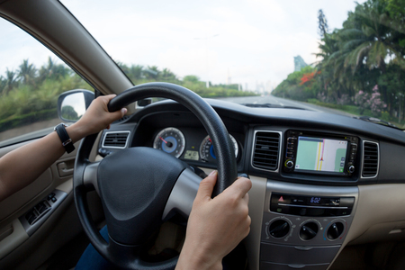 driver hands on wheel driving car on city streetの写真素材