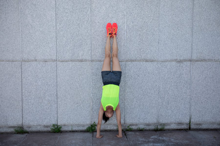 Sportswoman doing a handstand against a marble wall