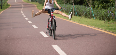Free woman cyclist riding bike in spring tropical park