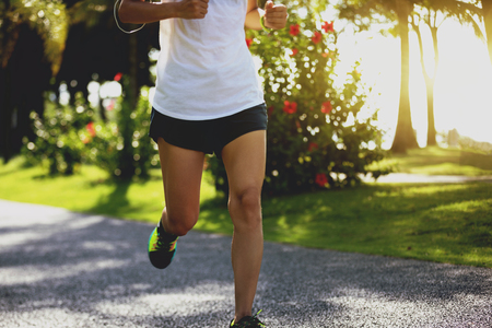 sporty fitness woman running at sunny parkの写真素材