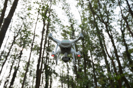 White drone with camera flying in tropical forest