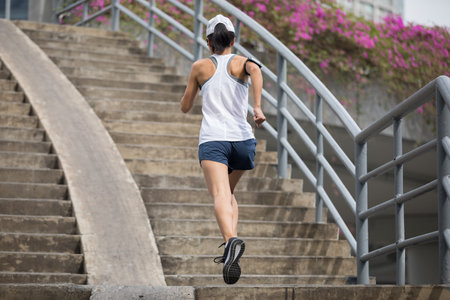 Young woman runner sportswoman running up city stairs