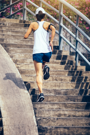Young woman runner sportswoman running up city stairsの写真素材