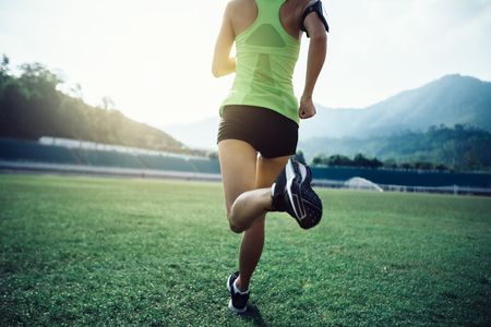 Fitness sportswoman running on stadium grassの写真素材