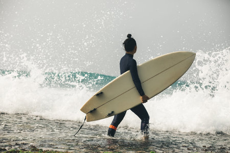 Woman surfer with surfboard going to surf the big wavesの写真素材