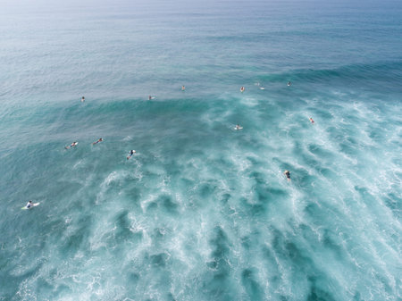 Top view from drone of many surfers waiting  to catch next wave during surf  in the indian ocean