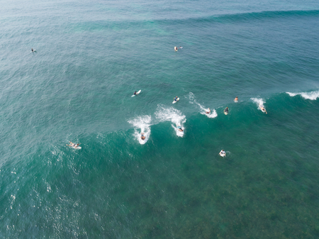 Top view from drone of surfers paddling for catching  waves during surfing  in the indian oceanの写真素材