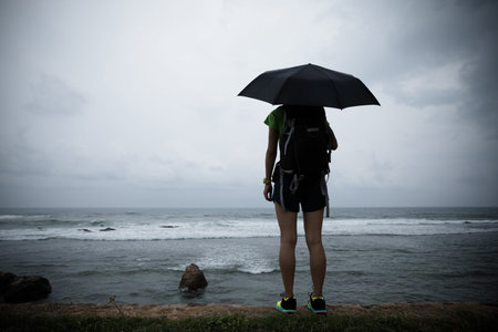 Woman with umbrella stand in the strom infront of sea