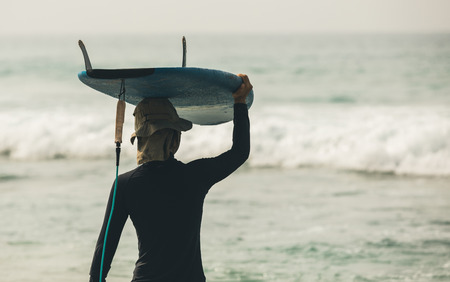woman surfer with surfboard in water looking at the coming wavesの写真素材