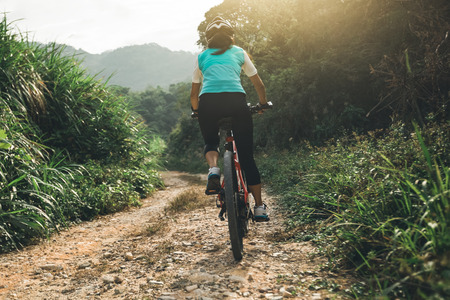 Woman cyclist riding a bike on a nature trail in the mountains.people living a healthy lifestyleの写真素材