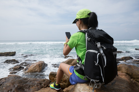 Woman Hiking In Seaside use mobile phoneの写真素材