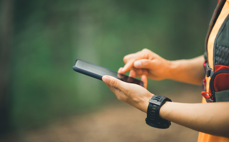 Sportswoman trail runner using smartphone for navigation in forestの写真素材