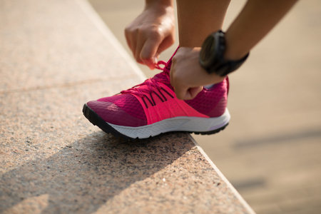 Fitness sportswoman tying shoelace on sunny coast