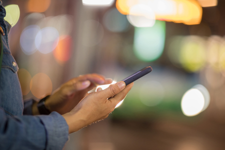 smart phone in woman hand on night city light backgroundの写真素材