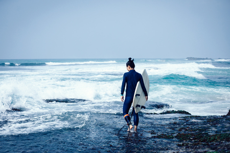 Woman surfer with surfboard going to surf the big wavesの写真素材