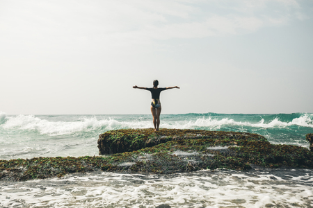 Freedom Woman outstretched arms at seaside mossy reefの写真素材