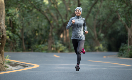 Woman running at winter park roadの写真素材