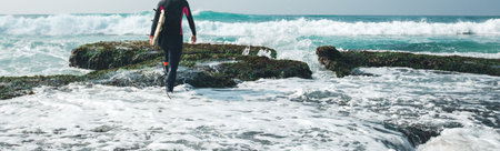 Woman surfer walking with surfboard on mossy coral reefs