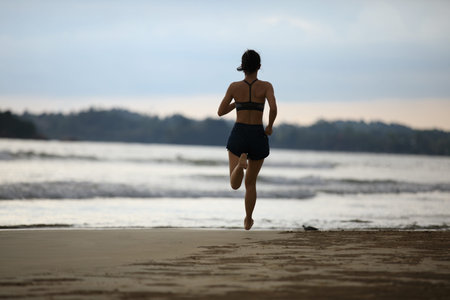 Female athlete running at sunset on beach