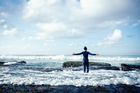 Freedom woman outstretched arms at seaside mossy coral reefの写真素材