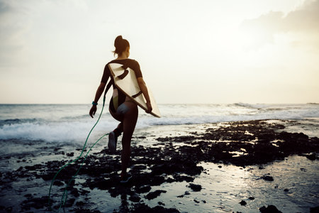 Woman surfer with surfboard going to surf
