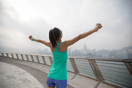 Healthy lifestyle woman runner outstretched arms on foggy city morningの写真素材