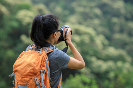 woman photographer taking photo on morning mountain forestの写真素材