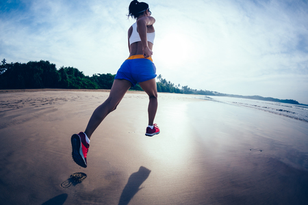 Fitness woman runner running on sunrise beachの写真素材