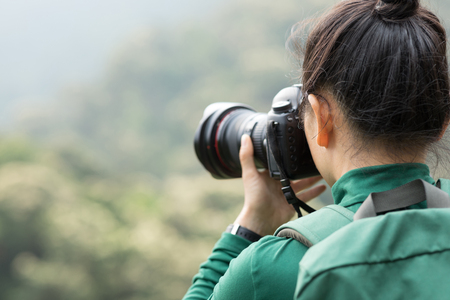 woman photographer taking photo on spring forest mountainの写真素材