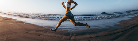 Fitness woman runner running on sunrise beachの写真素材
