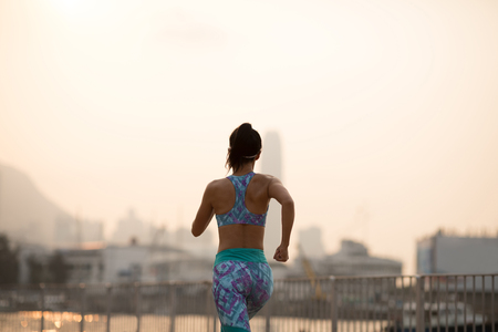 Healthy lifestyle woman runner running on foggy city at sunsetの写真素材