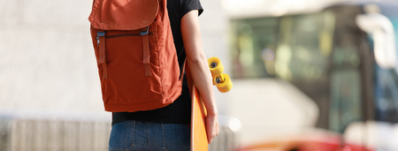 Woman walking with skateboard in hand on city streetの写真素材