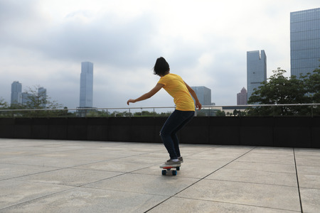 woman skateboarder skateboarding at cityの写真素材