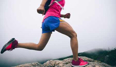 Healthy lifestyle woman ultra marathon runner running up to the seaside mountain topの写真素材