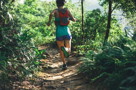 Young fitness woman ultramarathon trail runner running in summer forestの写真素材