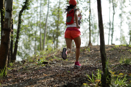 Young fitness woman runner running in forest