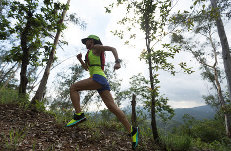 Sportswoman cross country ultra marathon trail runner running in forest