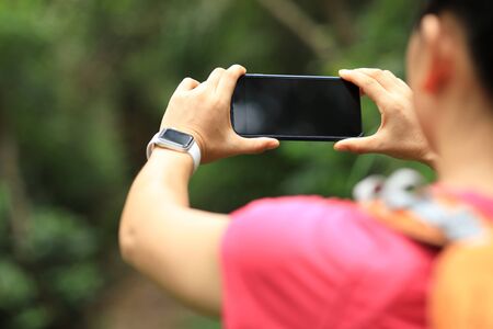 Woman hiker using smartphone taking pictures on hiking travelの写真素材