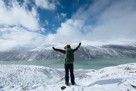 Cheering woman hiker hiking in snowing winter mountains