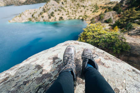 Hiker sit on cliff edge facing the beautiful high altitude lakeの写真素材