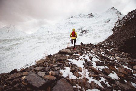 Woman trail runner cross country running up to winter snow mountain top
