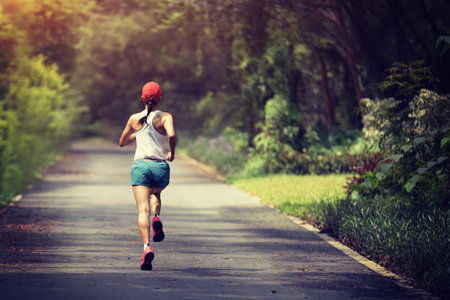 Fitness woman runner running at summer park trail . Healthy fitness woman jogging outdoors.の写真素材