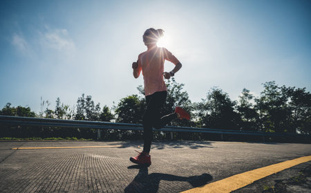 Woman runner running on mountain top on winter dayの写真素材