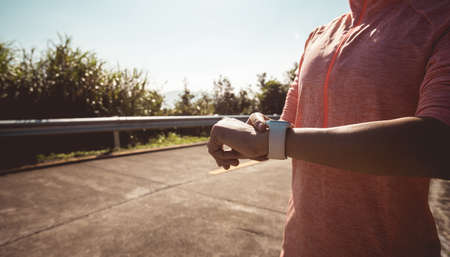 Woman runner set smartwatch on mountain top on winter dayの写真素材