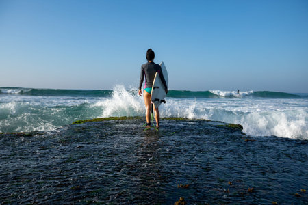 Woman surfer with surfboard going to surf at seasideの写真素材
