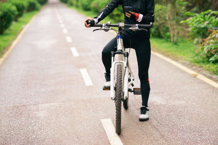 Cyclist use smartphone when riding mountain bike on forest trailの写真素材