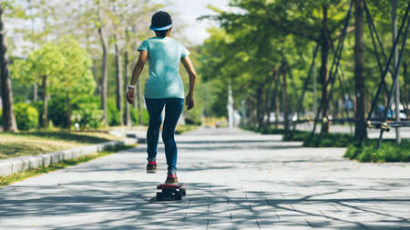 Asian woman skateboarder skateboarding in modern cityの写真素材